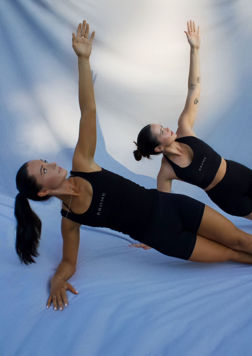 Two Krome instructors in a side plank with arms raised